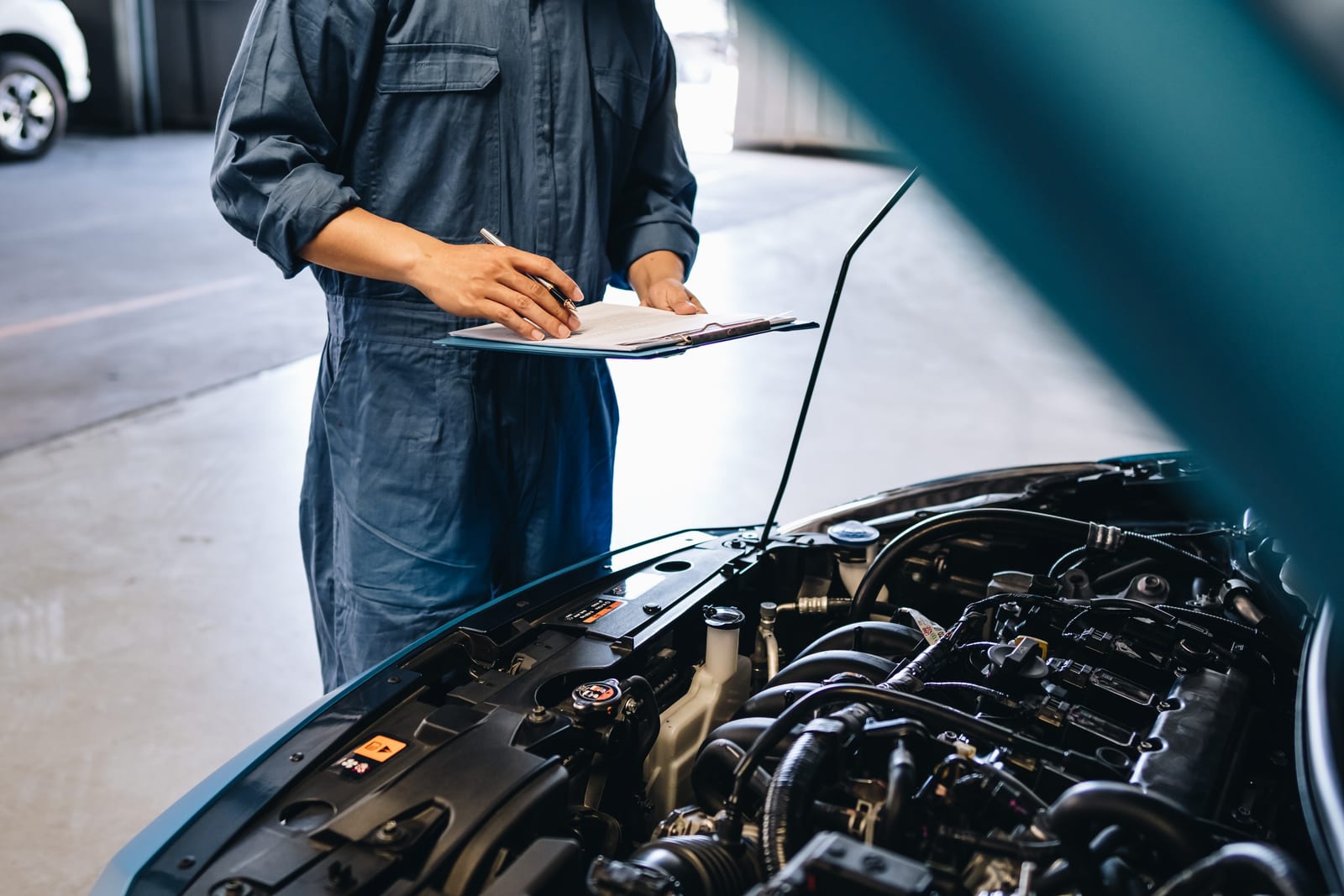 Mechanic with paperwork inspecting a vehicle engine at RWC HUB Yeerongpilly
